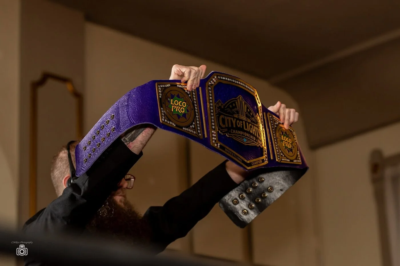 The purple and gold LoCo Pro championship raised above the ring
