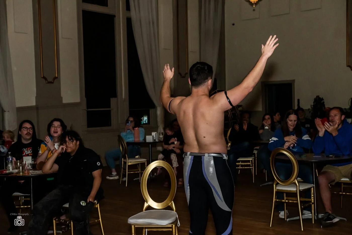 A wrestler raises his arms among cheering fans at ringside